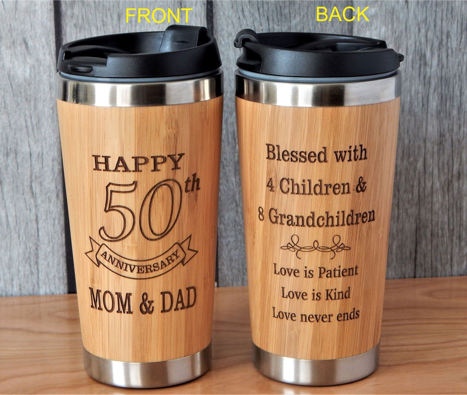 Two laser-engraved bamboo 50th anniversary travel tumblers with black lids, shown from the front and back against a gray wood background.