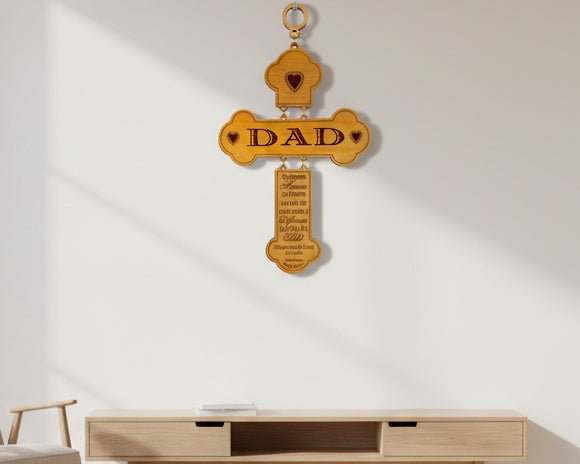 A personalized engraved wooden cross with the inscription 'DAD' and a heart symbol, mounted on a ring for hanging.