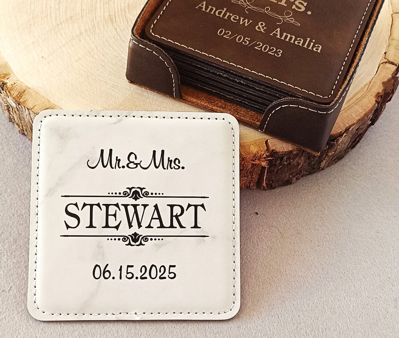 Personalized square coasters displayed on a wood slice background, with one white marble-look coaster in front reading 'Mr.&Mrs.