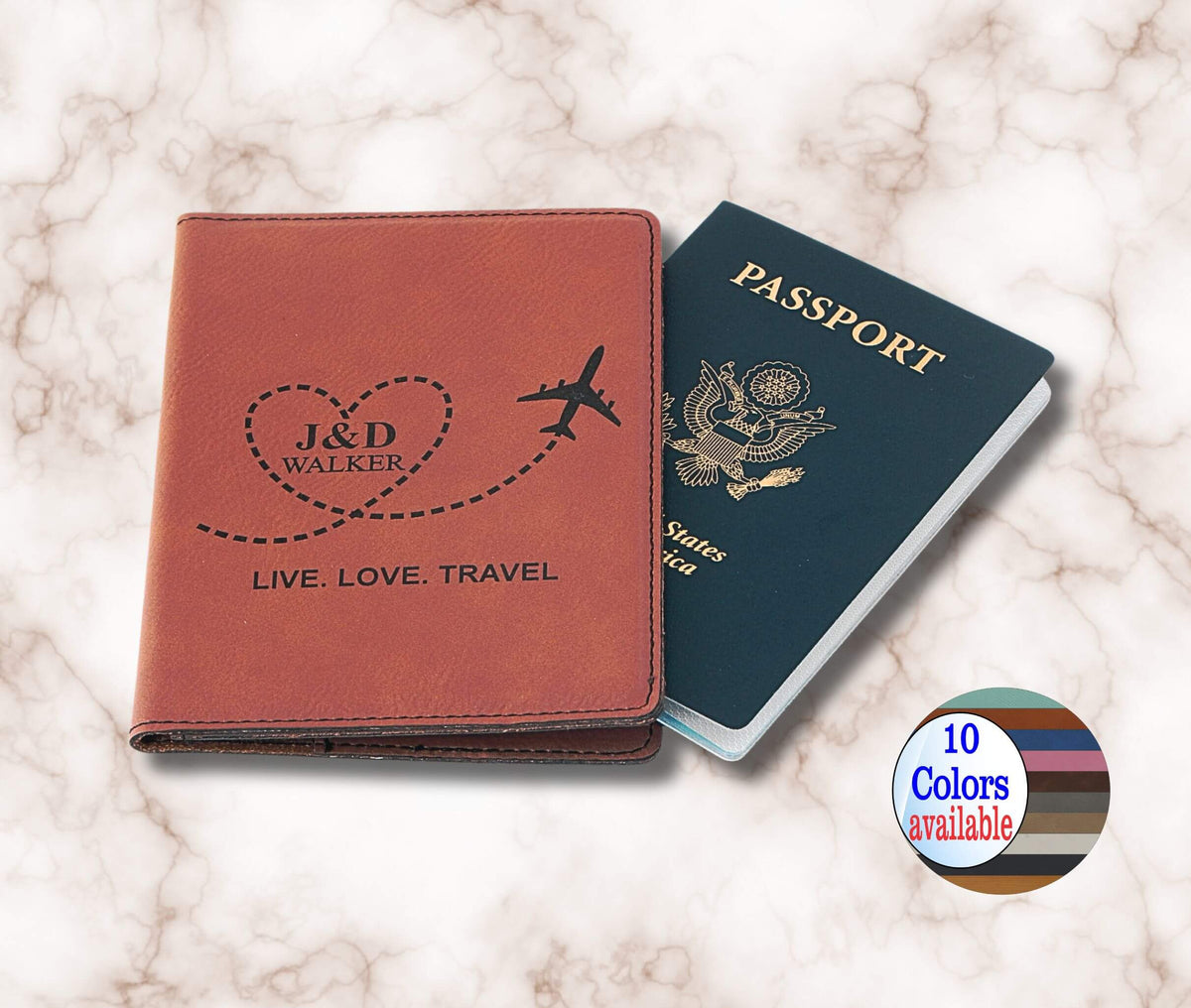 A personalized brown leather passport cover with an engraved heart, plane, and the names 'J&amp;D WALKER' on the front, shown next to a US passport on a white marble background. A circular badge in the bottom right corner reads '10 Colors available'.