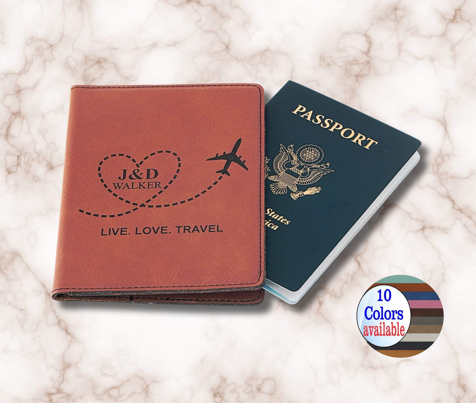 A personalized brown leather passport cover with an engraved heart, plane, and the names 'J&D WALKER' on the front, shown next to a US passport on a white marble background. A circular badge in the bottom right corner reads '10 Colors available'.