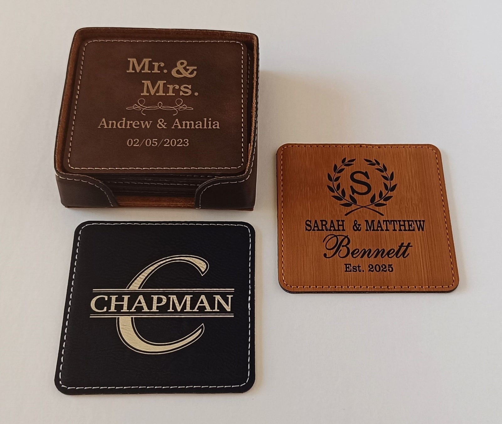 Three personalized leather coasters displayed on a light background: a dark brown boxed set engraved 'Mr. & Mrs.