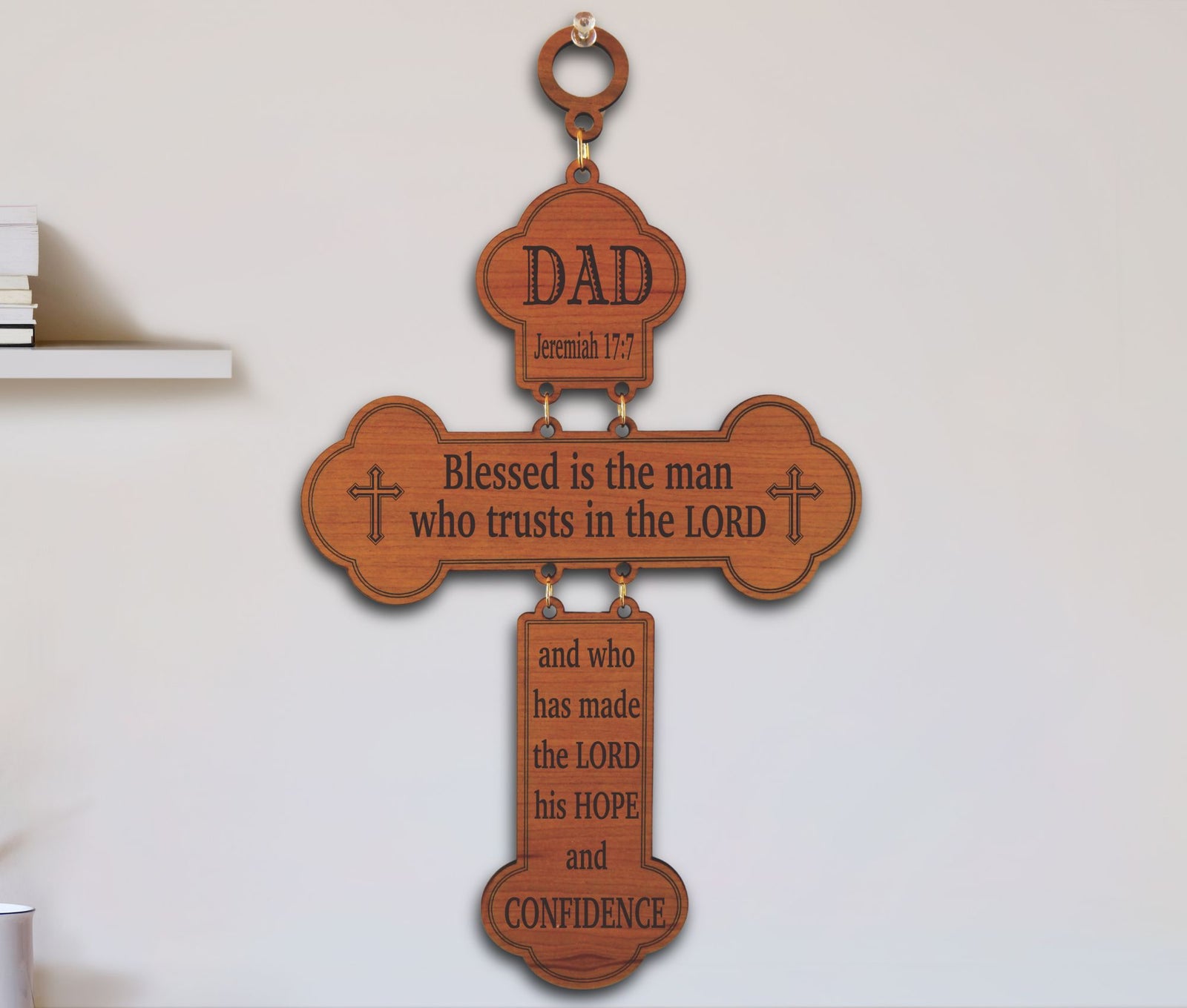 A wooden cross wall hanging with engraved Bible verses, including 'DAD' at the top and 'Blessed is the man who trusts in the LORD' across the center, shown hanging on a light wall.