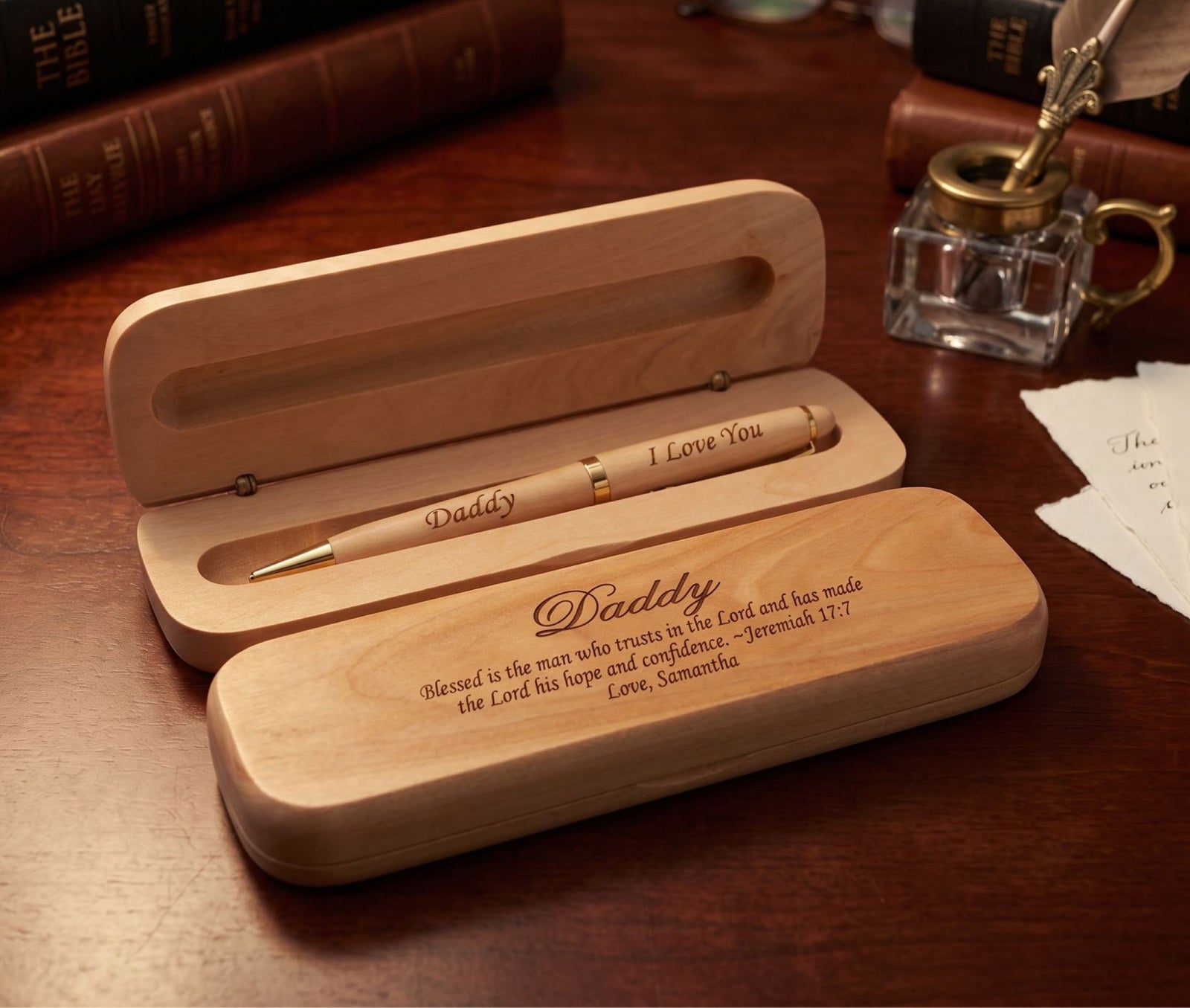 Personalized wooden pen and matching wooden case engraved with 'Daddy' and a Bible verse, displayed on a dark wood background.