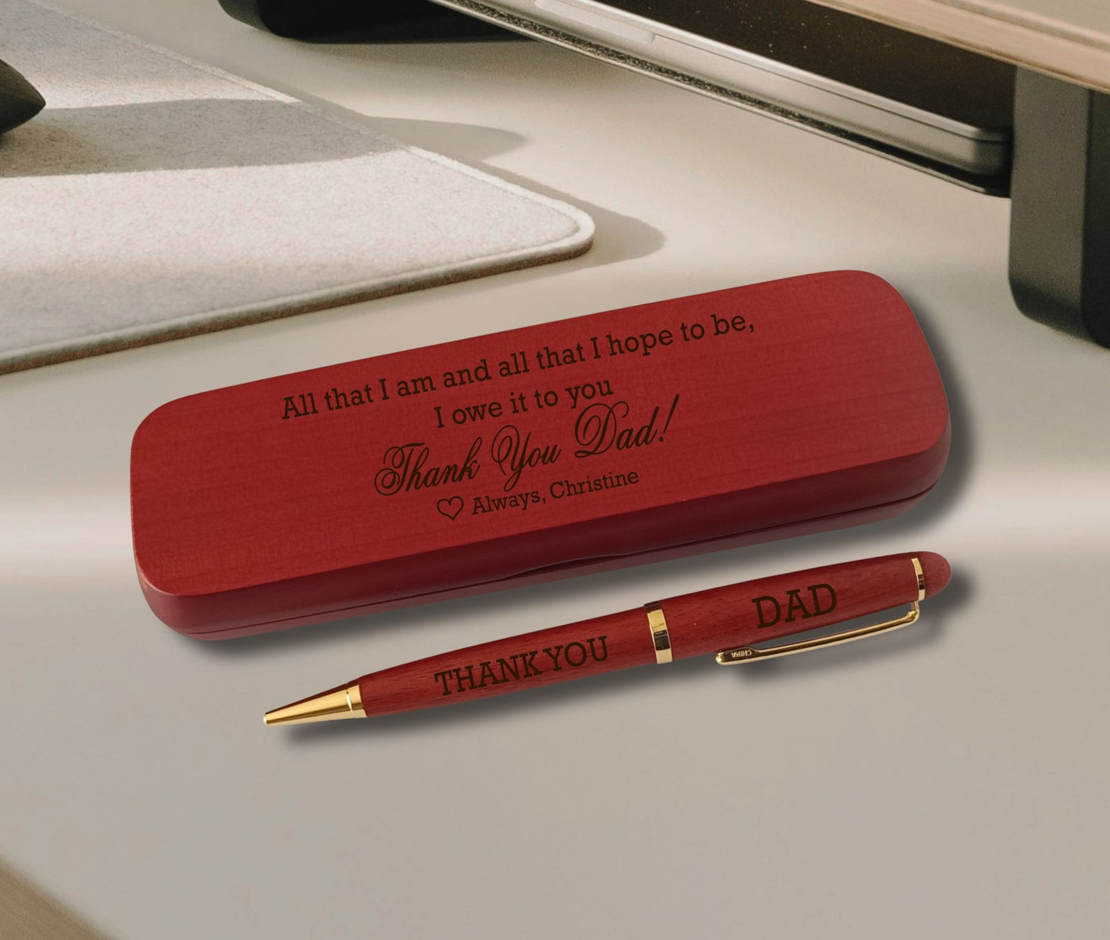 A personalized wooden keepsake box and matching pen set engraved with 'Thank You Dad!' and 'THANK YOU DAD', displayed on a light gray desk surface.