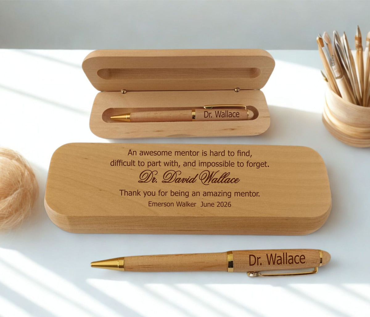 Personalized wooden pen gift set with engraved text on a light tabletop, including an open wooden case, a wooden pen with gold-toned metal accents, and a closed engraved wooden box.
