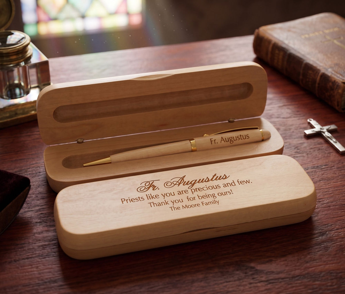A personalized wooden keepsake box set with a pen, shown open on a wooden table. The top lid features an engraved message for 'Fr.