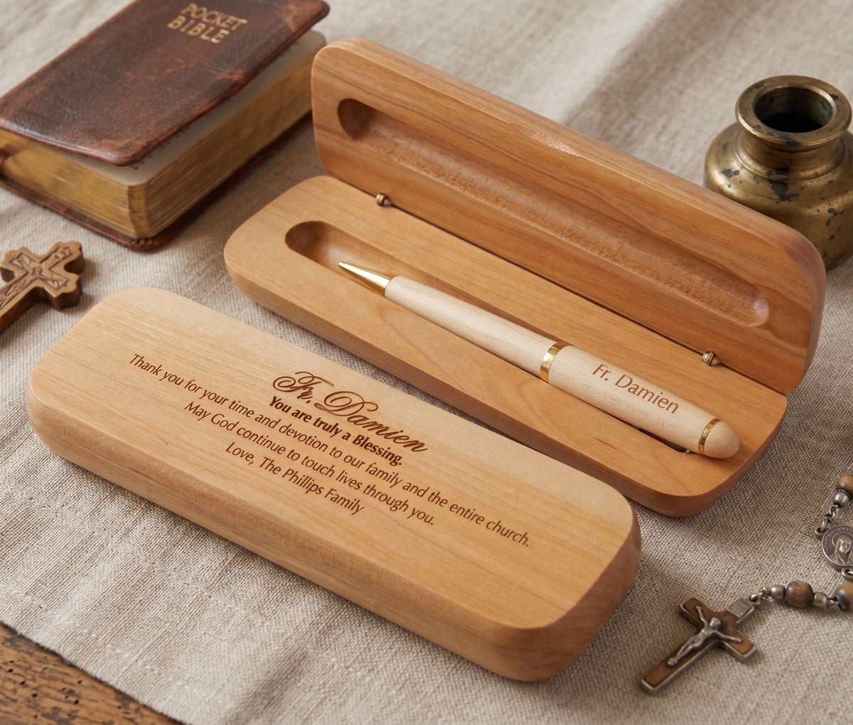 Personalized wooden keepsake box set with a pen, shown open and closed on a linen surface with religious props including a Bible, cross, and small vase.