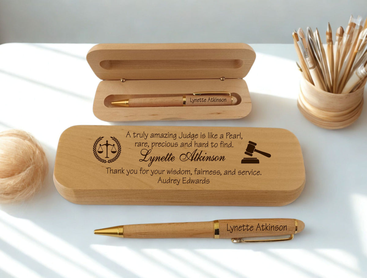 Personalized engraved maple wood pen and case set for a judge, featuring engraved name," scales of justice, gavel icons, and a custom dedication message, displayed open and closed on a white desk