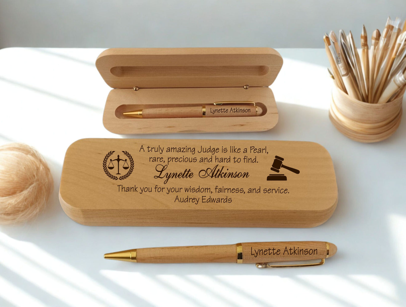 Personalized engraved maple wood pen and case set for a judge, featuring engraved name," scales of justice, gavel icons, and a custom dedication message, displayed open and closed on a white desk