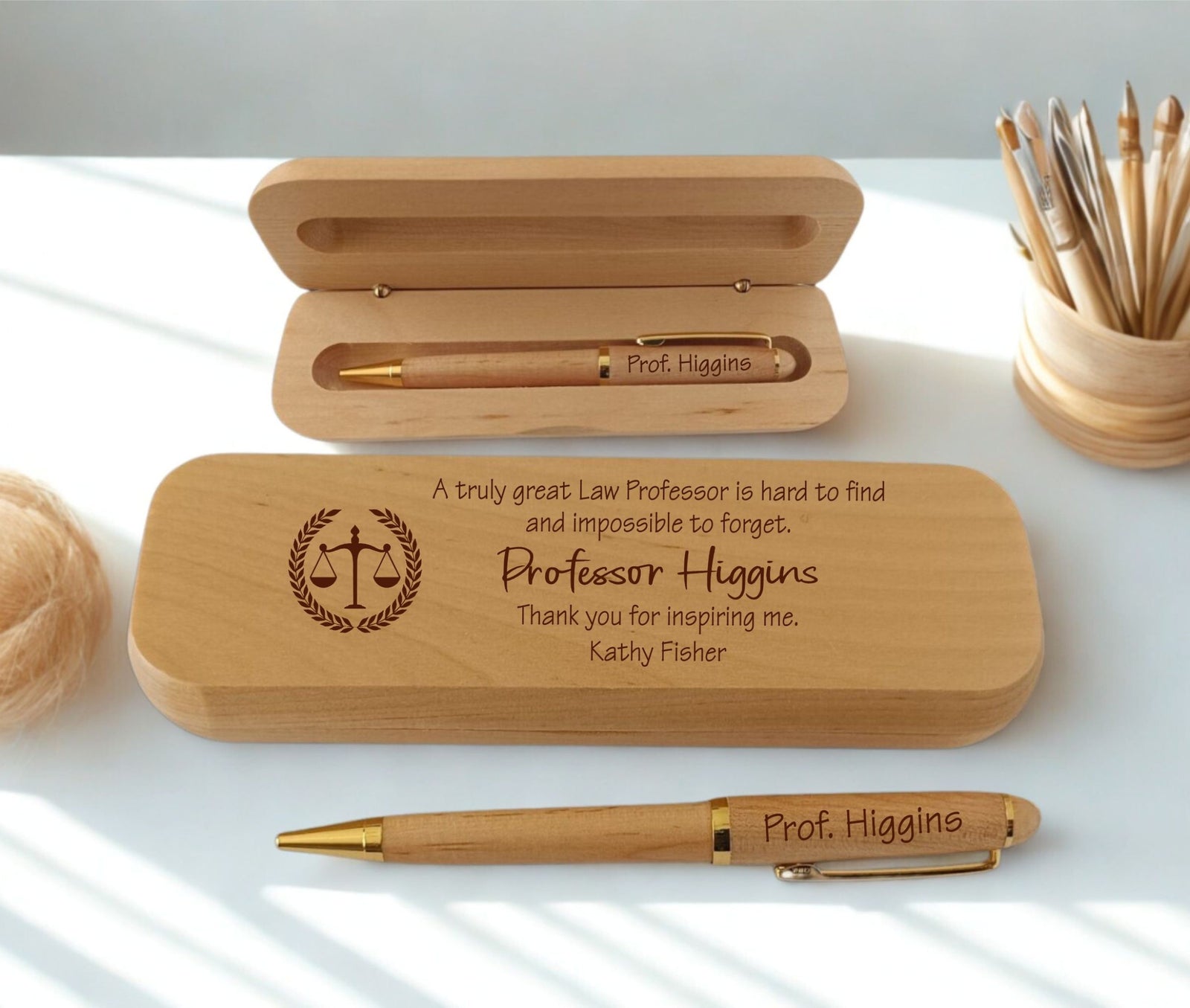 Personalized wooden pen gift set with engraved text and a scale of justice emblem, shown with an open wooden case and a matching pen on a white surface.