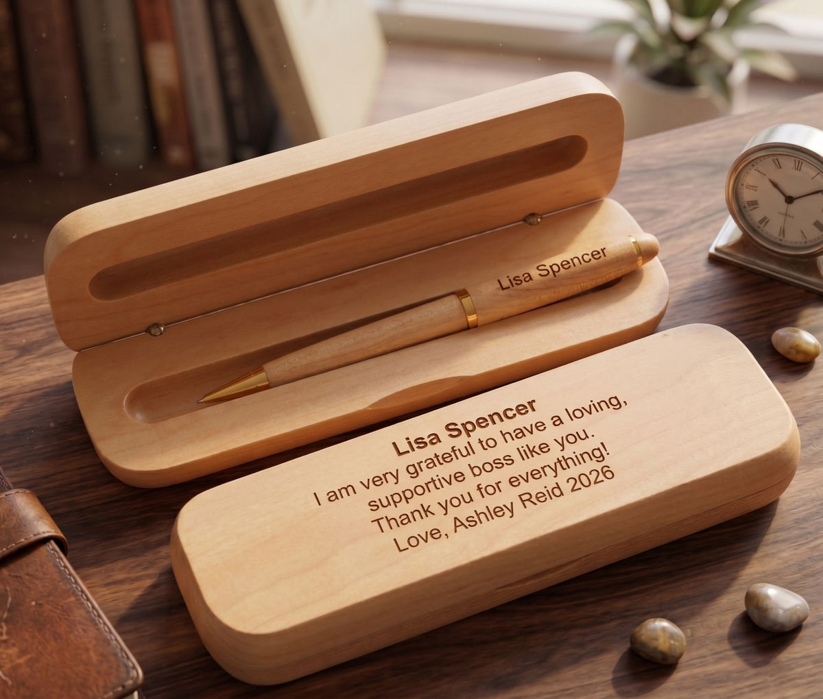 Personalized wooden pen and matching case set on a wooden desk, with the pen resting inside the open case and engraved text visible on both pieces.