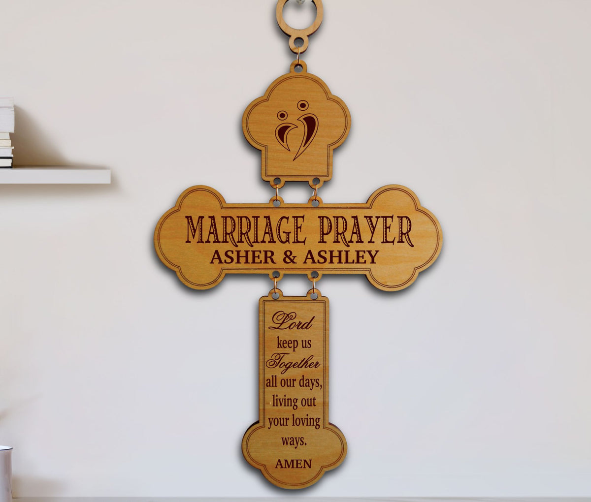 A personalized wooden cross wall hanging with engraved text reading 'MARRIAGE PRAYER ASHER &amp; ASHLEY' and a hanging plaque below with a prayer, shown against a plain light wall.