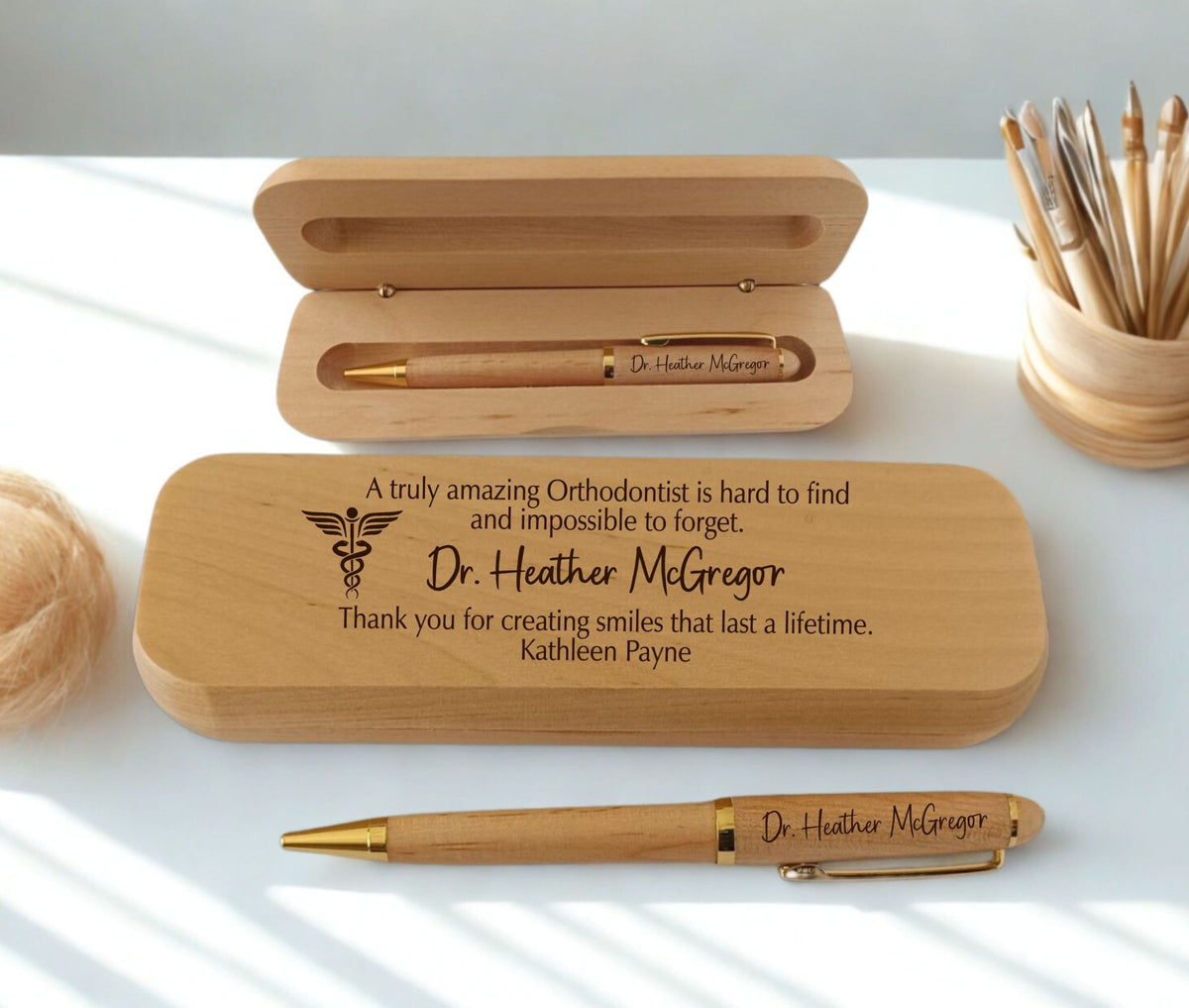 Personalized wooden pen gift set with an engraved wooden case and matching wooden pen with gold-tone metal accents, displayed on a white surface with soft natural shadows.