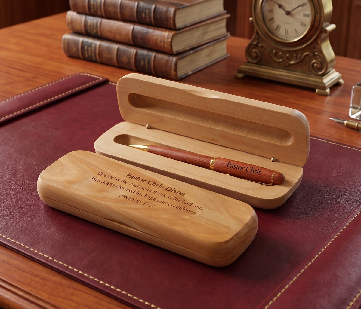 Personalized wooden pen gift set with an engraved wooden case and matching wooden pen box on a dark red desk mat, with books and a clock in the background.