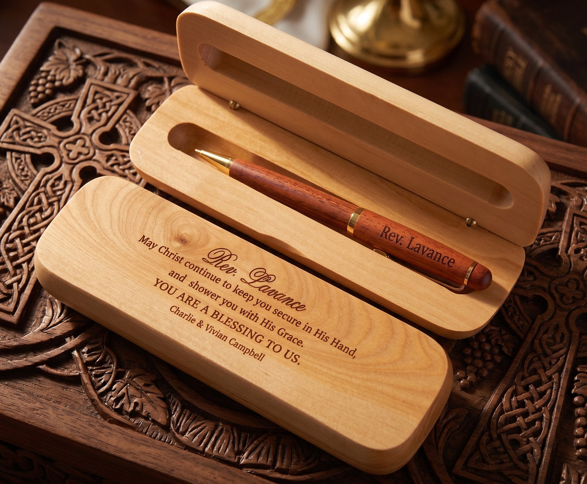 Personalized wooden pen gift set with an engraved wooden case and a wooden pen. The case lid is engraved with a religious message, and the pen is personalized with the name 'Rev.