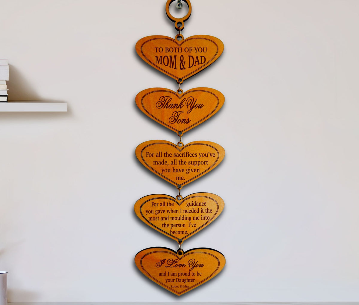 A vertical wooden wall hanging composed of five connected heart-shaped plaques with engraved memorial-style messages, mounted on a white wall.