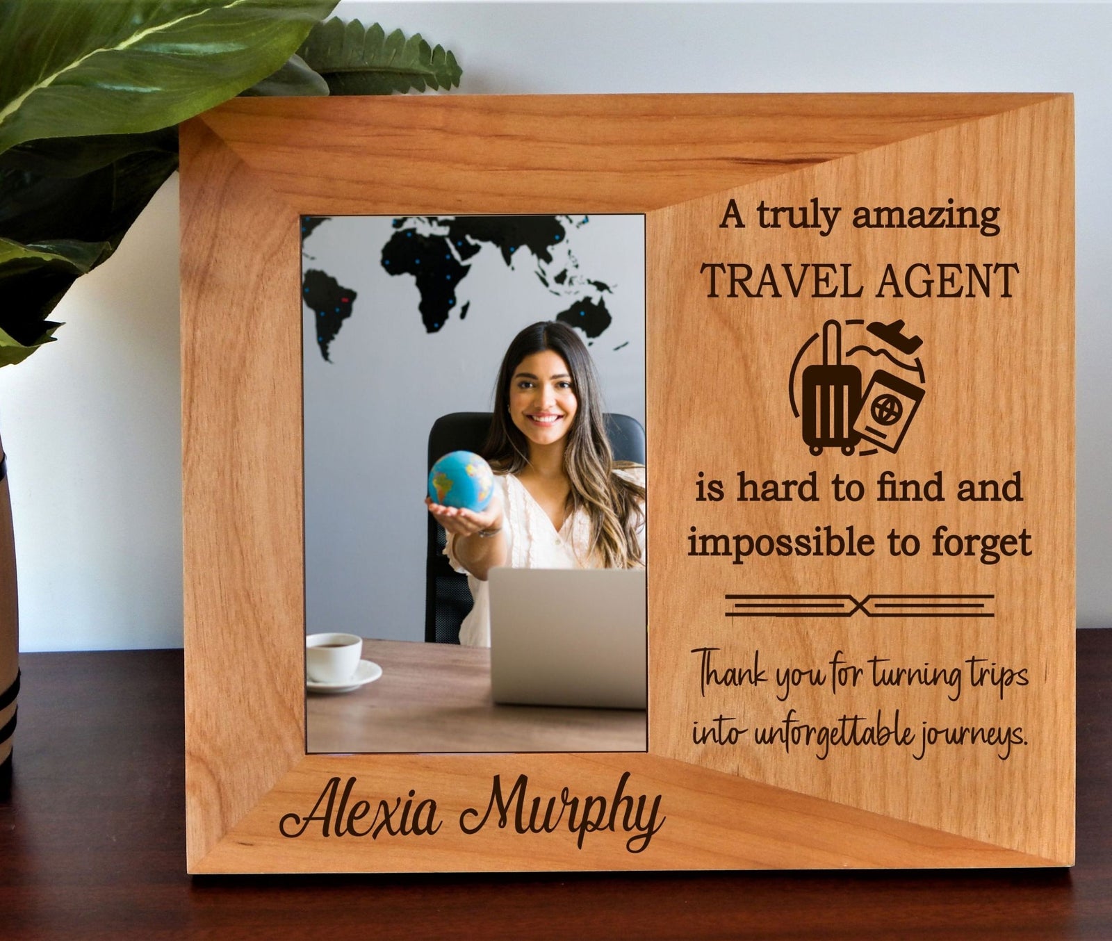 A personalized wooden plaque picture frame on a dark wooden table, featuring a photo of a smiling travel agent and engraved text thanking her.