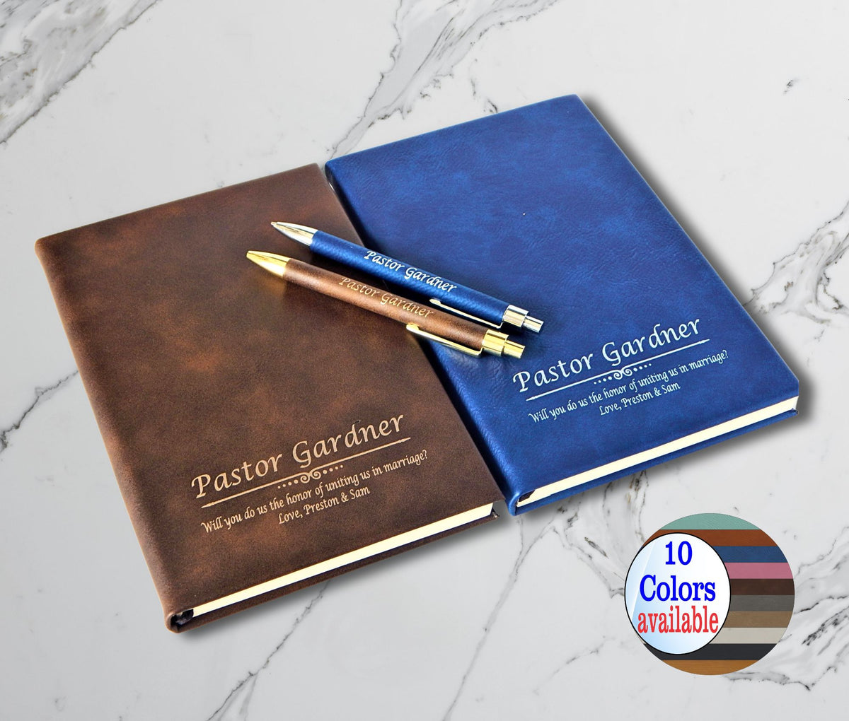 Two personalized hardcover wedding guest books in brown and blue leather-like finishes with matching pens, displayed on a white marble background. A circular badge in the corner indicates '10 Colors available'.