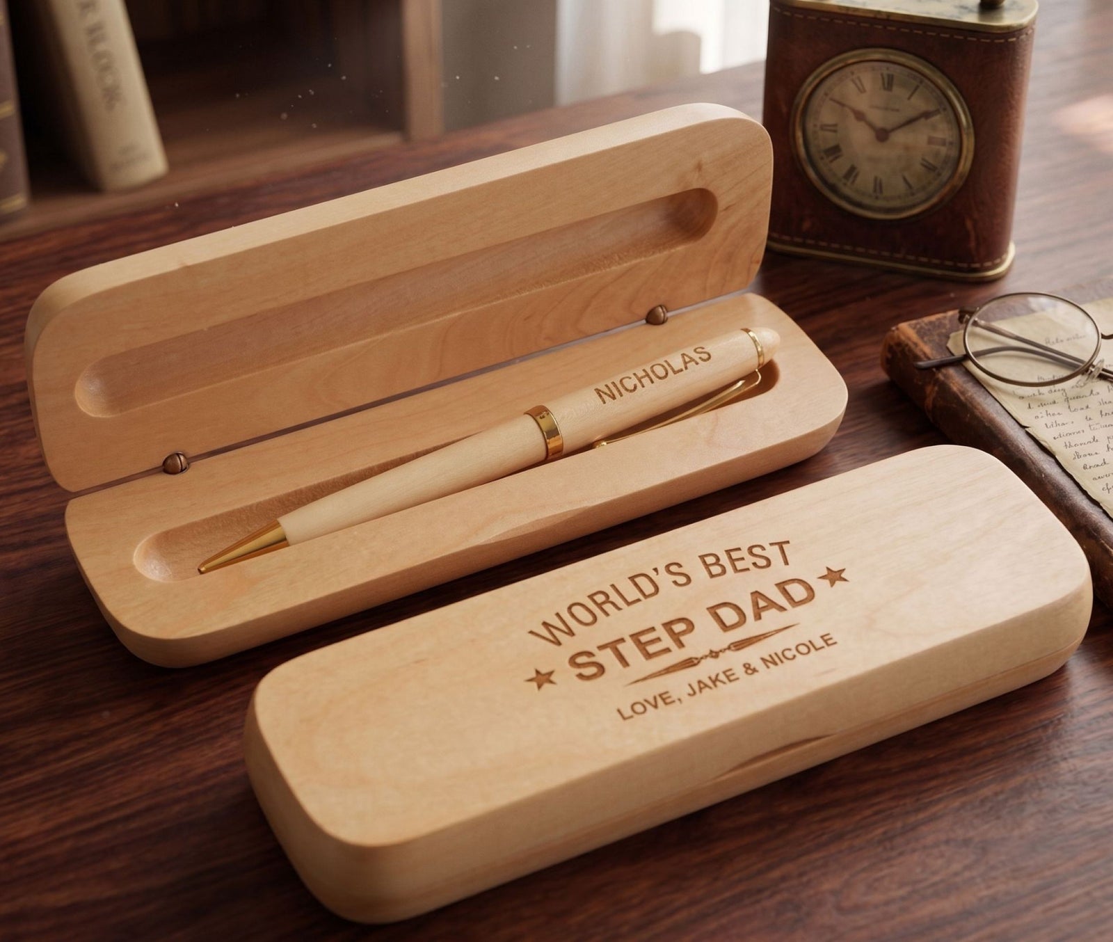 A set of personalized engraved wooden pens, with one pen placed in a case, showing an inscription on its side, and another pen placed outside the case, also with an inscription. The case is light brown with a branding stamp and a space for a personal message.