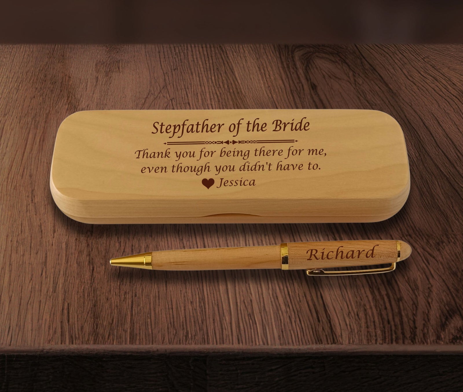 A personalized wooden pen and matching wooden case engraved with names and a message, displayed on a dark wood tabletop.