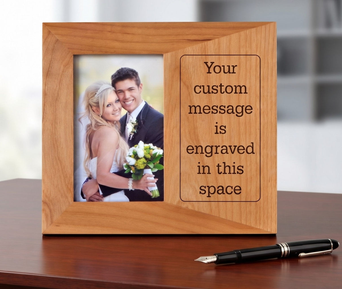 A personalized wooden picture frame with a photo of a bride and groom on the left and engraved placeholder text on the right, displayed on a wooden table with a black fountain pen in front.