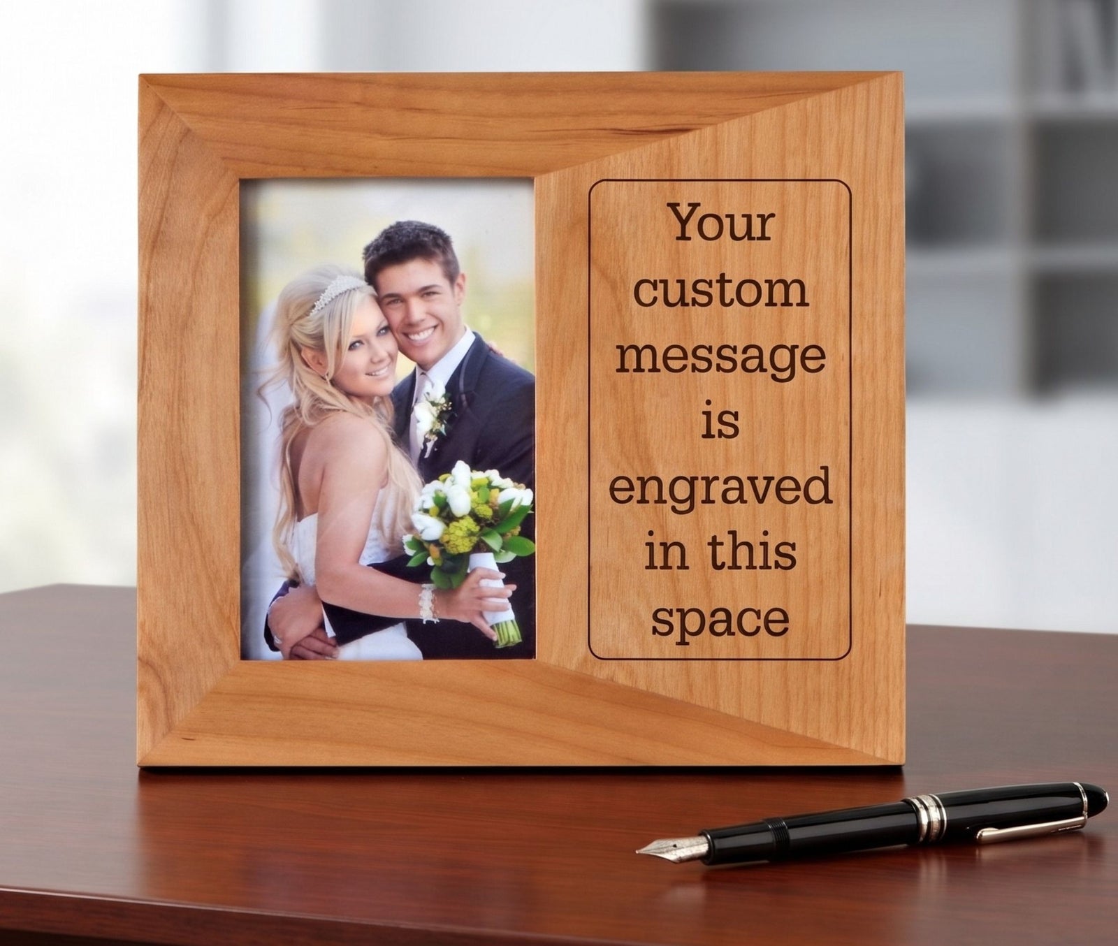 A personalized wooden picture frame with a photo of a bride and groom on the left and engraved placeholder text on the right, displayed on a wooden table with a black fountain pen in front.